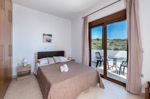 a bedroom with a bed and a balcony with a table at Villa Kiotari by Villa Plus in Kiotari