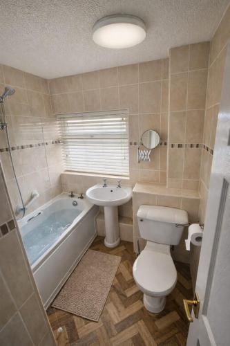 a bathroom with a toilet and a tub and a sink at Cloverdale in Bedlington