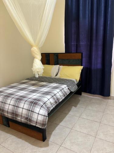a small bed with a plaid blanket and curtains at Next Level in Gulu