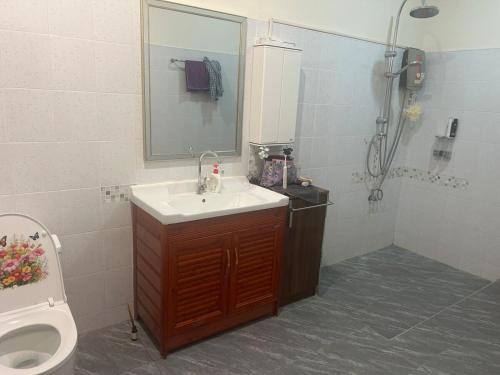 a bathroom with a sink and a toilet and a mirror at Baan Farang in Samut Songkhram