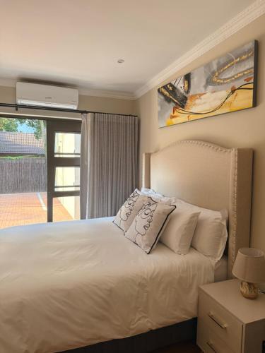 a bedroom with a white bed and a window at Cathy & P Guesthouse in Hartbeespoort