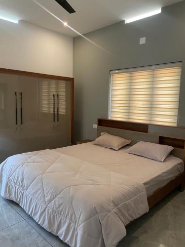 a bedroom with a large white bed and a window at Vijay Home Stays in Batheri