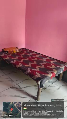 a bed in a room with a pink wall at Sukhram ji ka awas in Morādābād