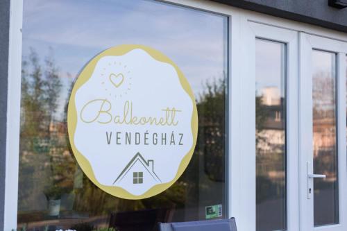 a sign in the window of a restaurant with a house at Balkonett Vendégház in Balatonfüred