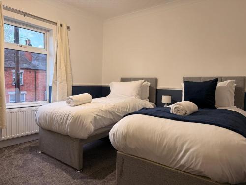 two beds in a room with a window at Contractor Friendly 4 Bed House XBOX Sleeps 6 in Newark-on-Trent