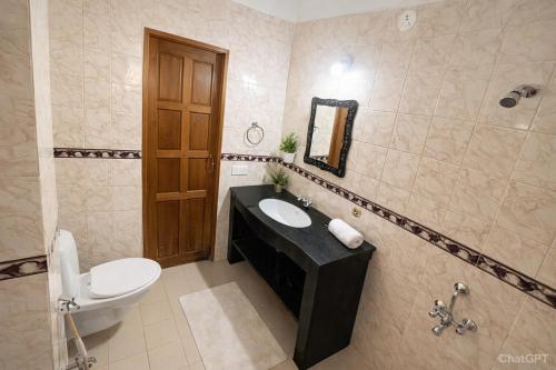 a bathroom with a sink and a toilet and a mirror at Abraham's 4 BHK villa, By Gonserv in Jāmb