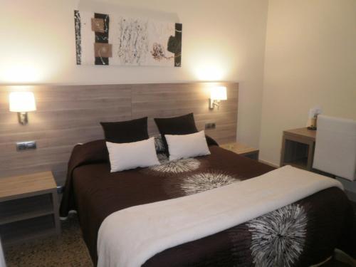 a bedroom with a large bed with two tables at Hotel Victor in Rialp