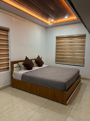 a bedroom with a large bed with two windows at ARAMAM SERVICE VIlla in Mananthavady