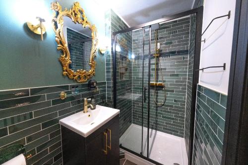 a bathroom with a sink and a shower with a mirror at Ricky Road Guest House in Watford