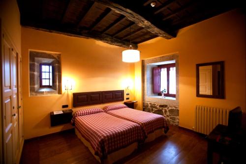 a bedroom with a bed and two windows at Rectoral de Castillon in Pantón