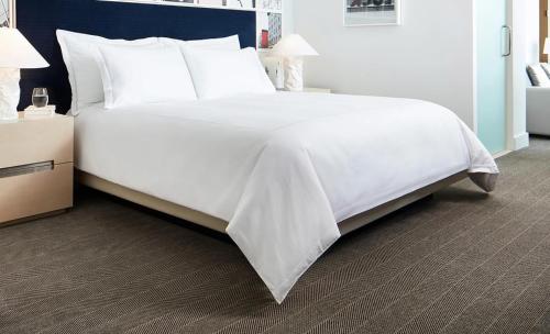 a large white bed with white sheets and pillows at Latitudo Suites Uganda in Kajansi