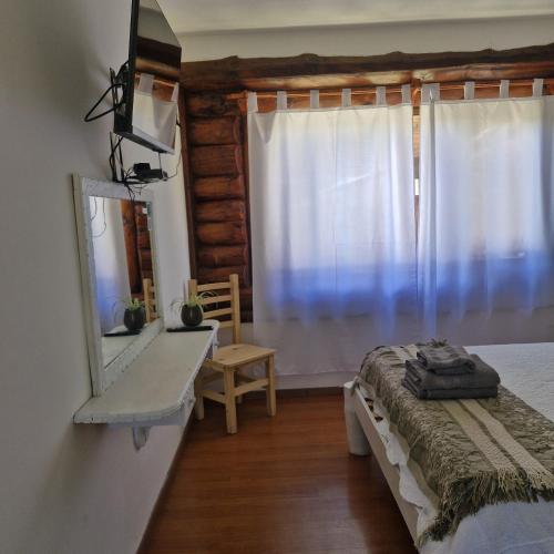 a bedroom with a bed and a mirror and a window at Hosteria EL REFUGIO in Aluminé