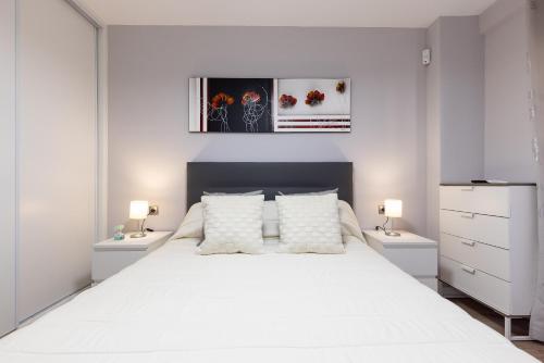 a bedroom with a large white bed with two night stands at FORMENTOR Apartment in Salou