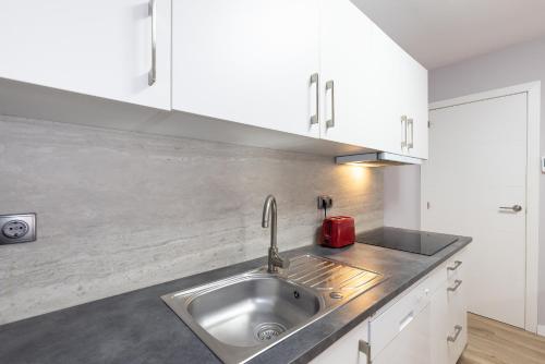 a kitchen with a stainless steel sink and white cabinets at FORMENTOR Apartment in Salou