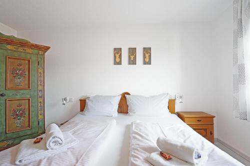 a bedroom with a bed with white sheets and towels at Am Mühlbach in Nesselwang