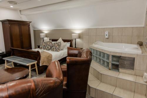 a hotel room with a tub and a bed and chairs at St Andrews exclusive guesthouse in Klerksdorp