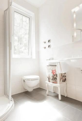 a white bathroom with a toilet and a sink at Pension Lutter in Bodenwöhr