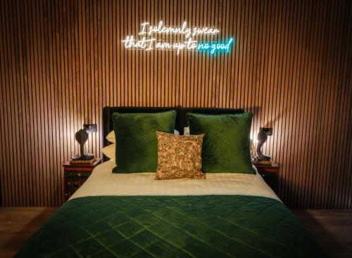 a bedroom with a bed with green sheets and a neon sign at Ricky Road Guest House in Watford
