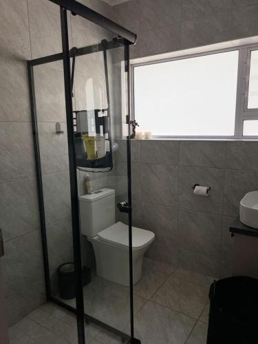 a bathroom with a toilet and a glass shower at Villa Bella in George