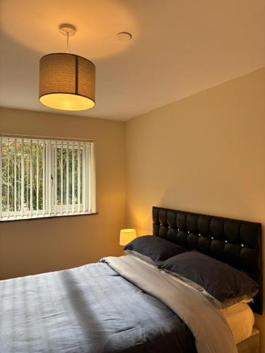 a bedroom with a bed and a lamp and a window at Castell Cottages Central with Parking in Caerphilly