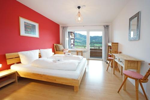 a bedroom with a white bed and a red wall at Panoramaweg in Wertach