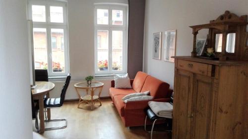 a living room with an orange couch and a table at Ferienhaus Wismar in Wismar