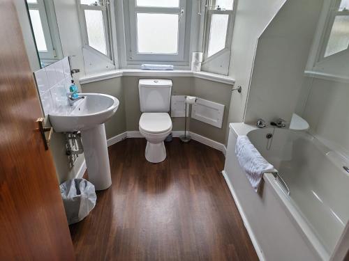 a bathroom with a toilet and a sink and a tub at Chieftain Hotel in Inverness