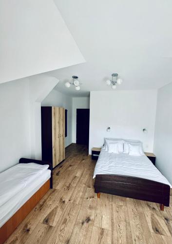 a bedroom with two beds and a wooden floor at Willa u Marioli in Ściegny