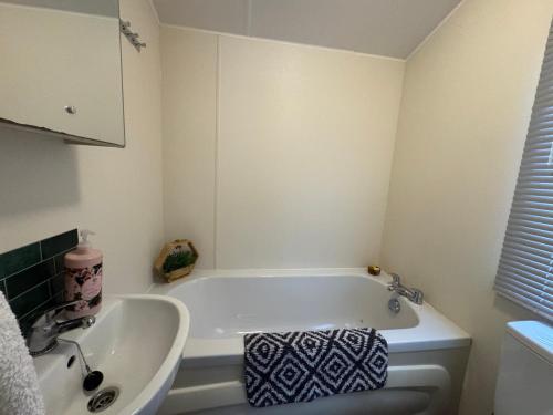 a white bathroom with a tub and a sink at Northcott 59, Bude in Poughill