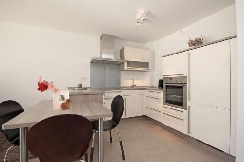 a kitchen with white cabinets and a table and chairs at N-Appartement Falkenstein in Nesselwang