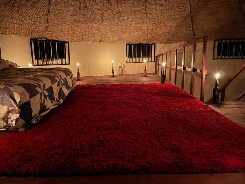 a bedroom with a large red rug on the floor at Tida-Ecolodge in Kartung