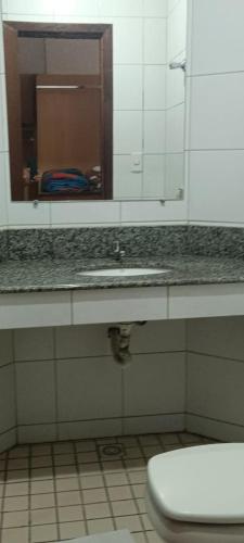 a bathroom with a sink and a toilet with a mirror at Gutemberg Palace Hotel in Nova Serrana