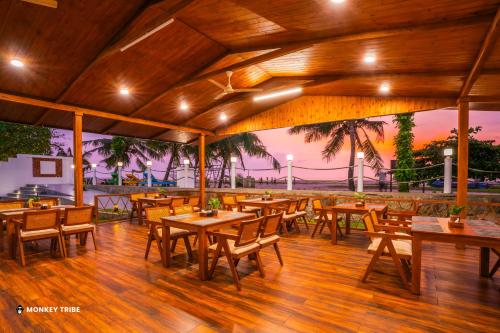 a restaurant with wooden tables and chairs on a wooden floor at Monkey Tribe Alleppey in Alleppey