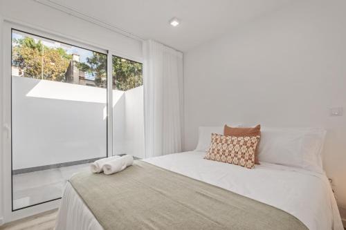 a white bedroom with a bed and a large window at Brito's Guest House - Monthly Rentals & Digital Nomads in Funchal