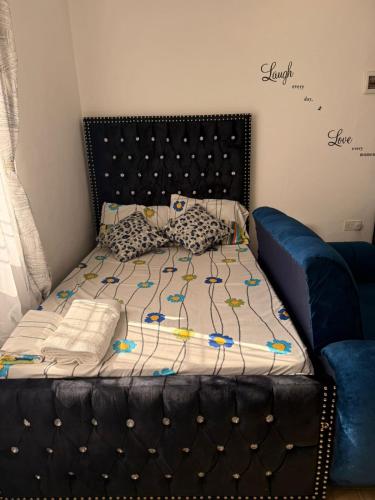 a bed with a black headboard and pillows on it at JnG HOMES in Malindi