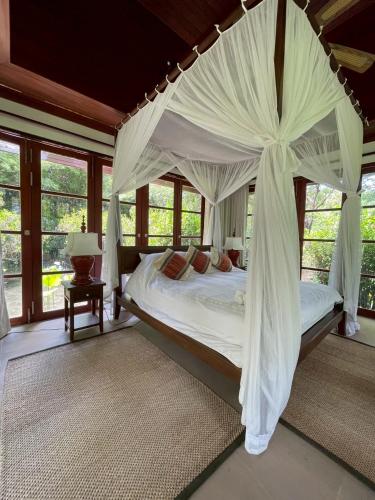 a bedroom with a large bed with a canopy at Baan Na Villa in Satuk