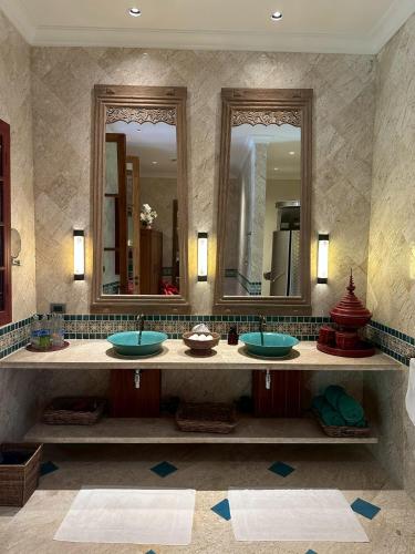 a bathroom with three sinks and two mirrors at Baan Na Villa in Satuk