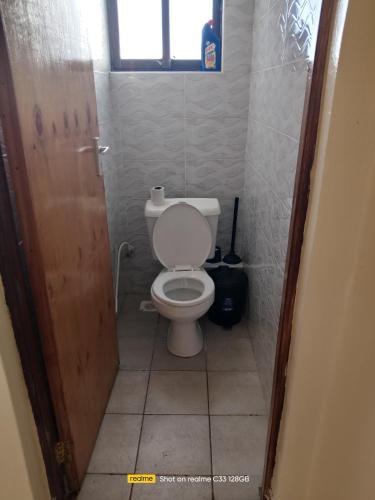 a small bathroom with a toilet and a window at Luxury Homes in Mtwapa
