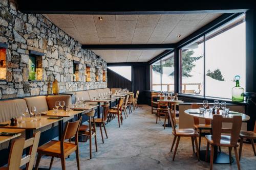 a restaurant with tables and chairs and a stone wall at La Cachette, Friendly Hotel & Spa in Arc 1600