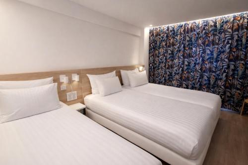 two beds sitting next to each other in a room at Geographotel Paris-Roissy CDG Airport in Le Mesnil-Amelot