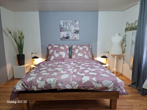a bedroom with a bed with a purple comforter at Ferienwohnung Seeblick in Langweiler