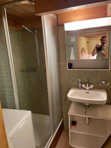 a man taking a picture of a bathroom with a sink and shower at Lake view Chalet , Drligen in Därligen