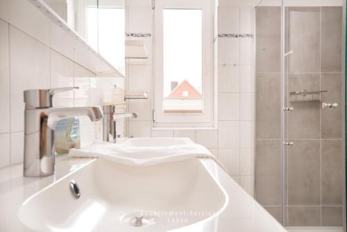 a white bathroom with a sink and a shower at Seewind W04 in Laboe