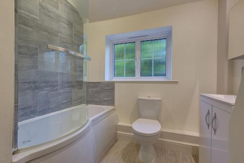 a bathroom with a toilet and a tub and a sink at Rose Cottage in Docking