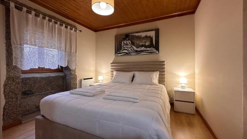 a bedroom with a large white bed and a window at Casa da Tia Palmira in Castelo de Paiva