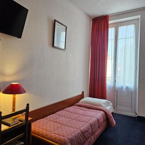 a hotel room with a bed and a window at Hotel du Commerce et de Navarre in Lourdes