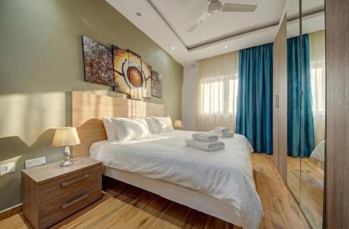 a bedroom with a large white bed with blue curtains at Tigné Seafront Apartments & Penthouse with Heated Jacuzzi in Sliema