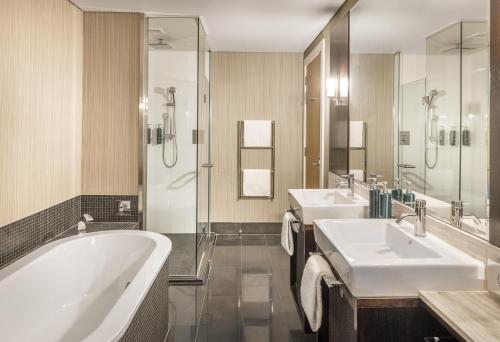 a bathroom with two sinks and a tub and a shower at Hilton Queenstown Resort & Spa in Queenstown