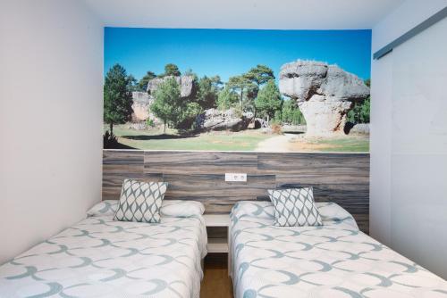 a bedroom with two beds and a painting on the wall at New Hostal Cabañas in Carboneras de Guadazaón