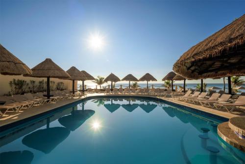 a swimming pool with chairs and umbrellas at a resort at Occidental Tucancún - All Inclusive in Cancún